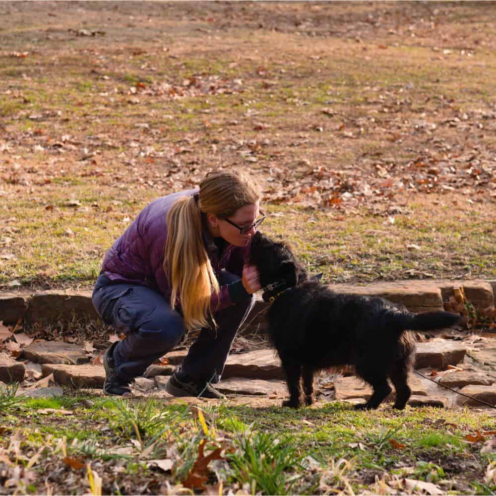 Woman training black puppy outdoors in Tulsa, Oklahoma.